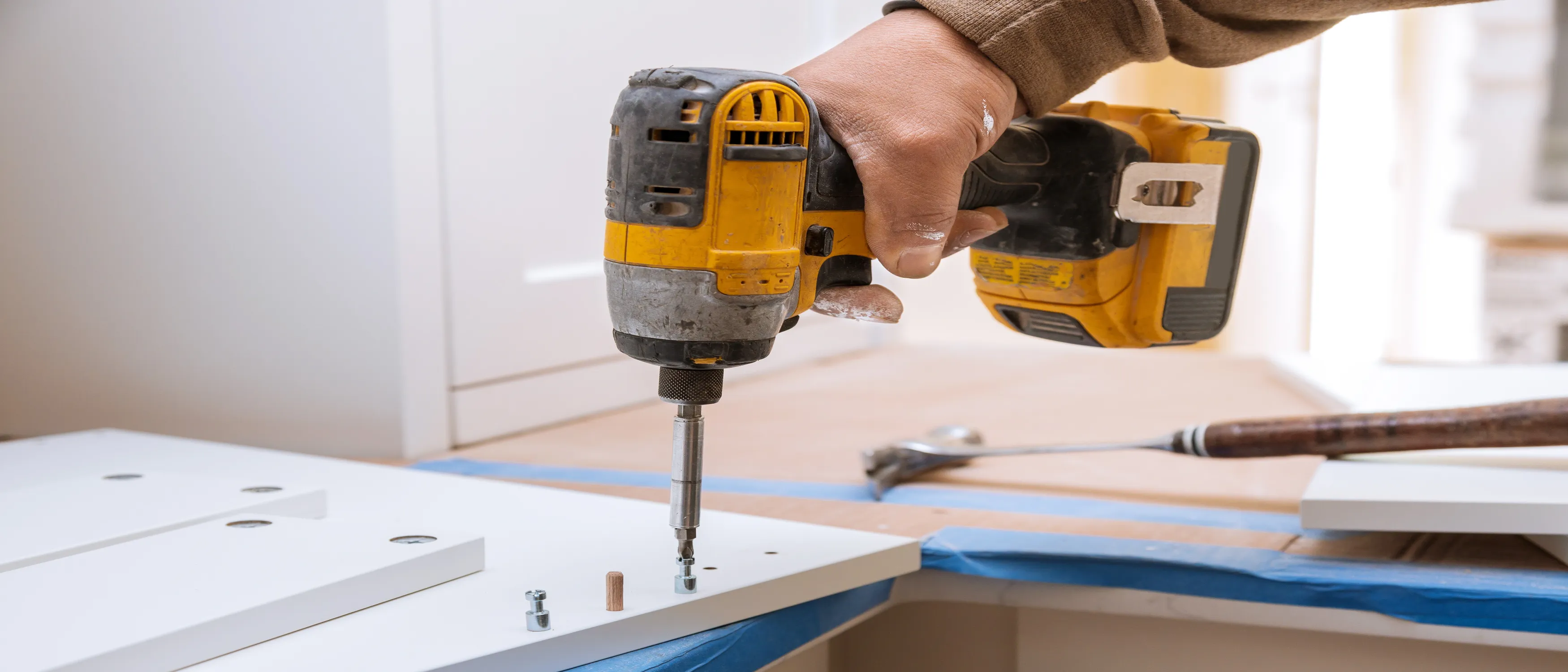 worker using drill to repair kitchen cabinet